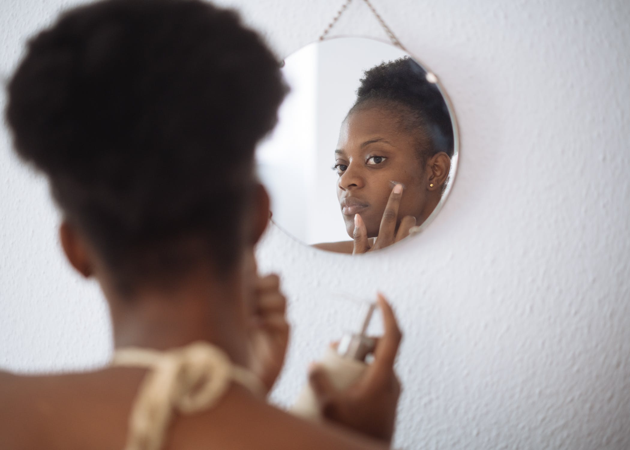 woman using skincare in mirror